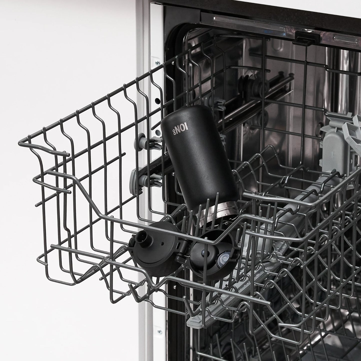 A black bottle labeled "ION8" stands upright in an open dishwasher rack inside a kitchen setting.