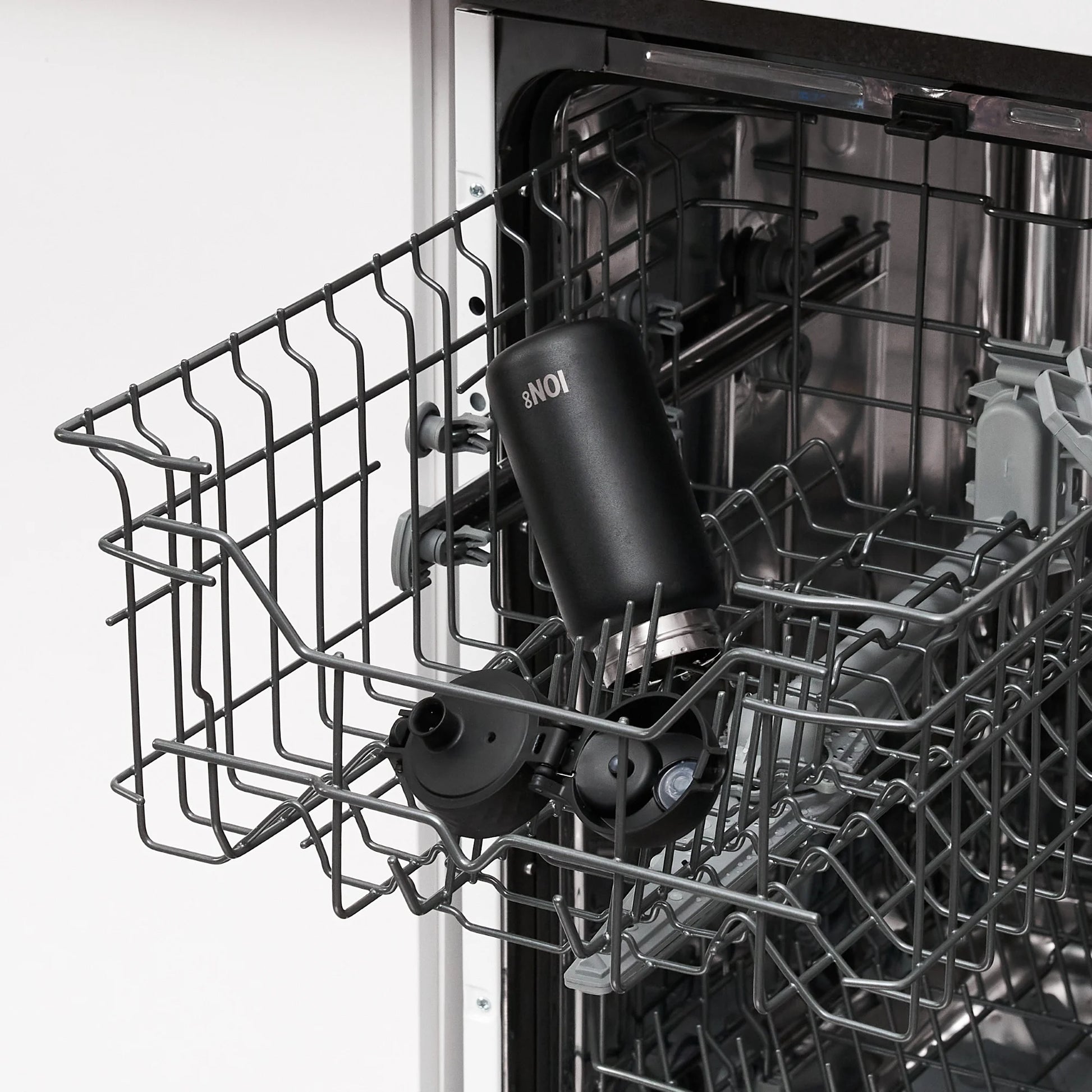 A black bottle labeled "ION8" stands upright in an open dishwasher rack inside a kitchen setting.