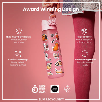 A pink water bottle, featuring a carry handle and dog stickers, is being held against a pink background. Award Winning Design. Hide-Away Carry Handle. No rattles, never in the way. Hygiene Cover. Keeps the spout safe and clean. Crevice Free Design. Designed with hygiene in mind. Wide Opening Mouth. Easy clean, easy refills. GERMAN DESIGN AWARD WINNER 2024. GOOD DESIGN. 2021. SLIM RECYCLON™.