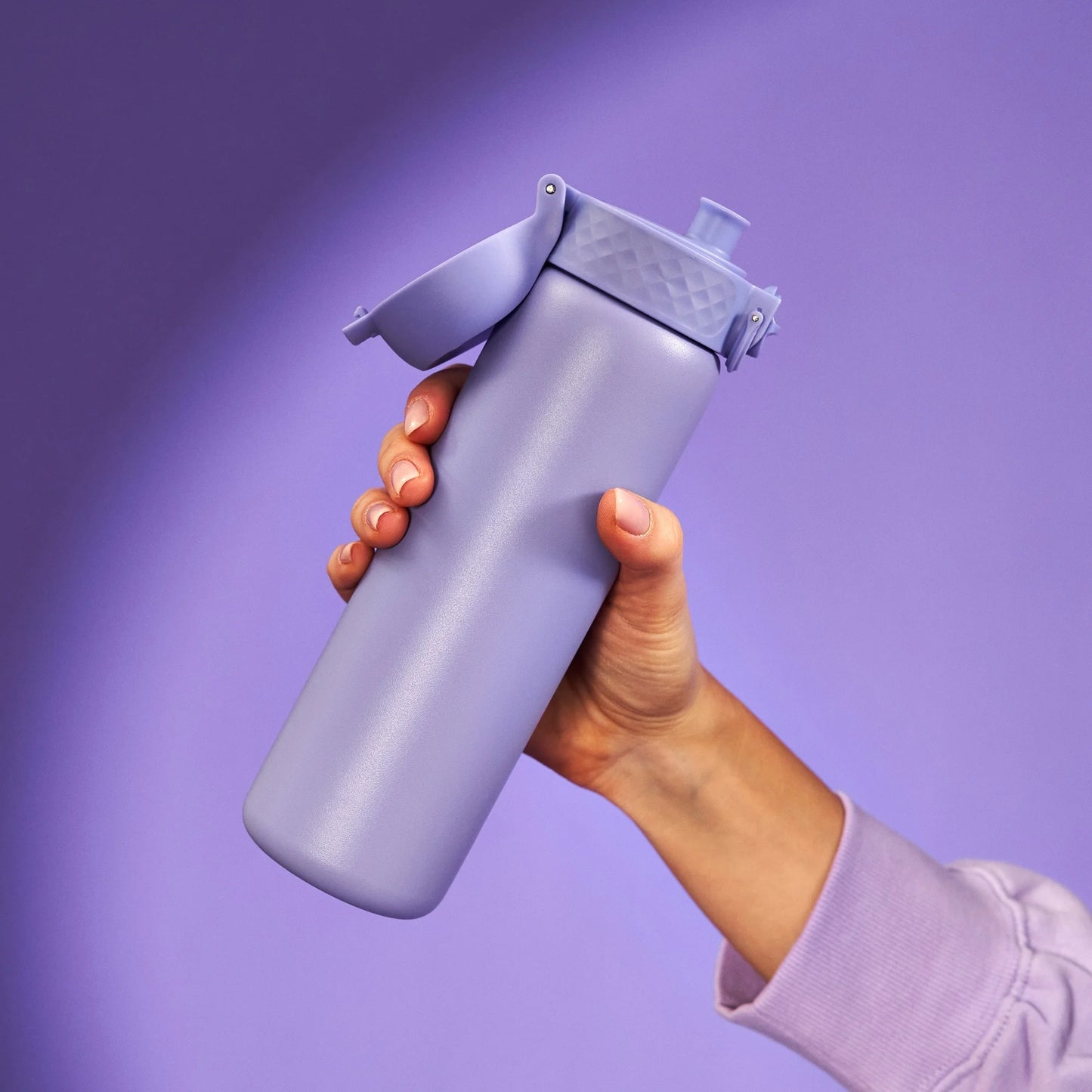 A hand holding a lavender-colored water bottle with a flip-top lid against a matching lavender background.