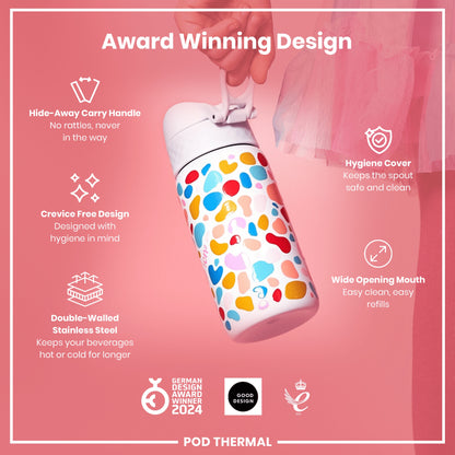 A colorful, double-walled stainless steel water bottle is being held against a pink background. The bottle features an award-winning design with a hide-away carry handle, crevice-free design, hygiene cover, and wide opening mouth. GERMAN DESIGN AWARD WINNER 2024, GOOD DESIGN, and 2021 logos are visible.