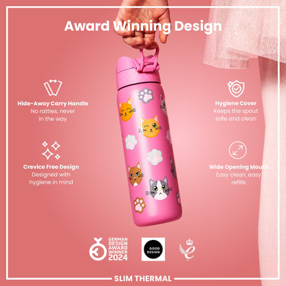 A pink, cat-themed water bottle is being held against a pink background. It features a hide-away handle, hygiene cover, and wide mouth. Awards are shown below. Award Winning Design. Hide-Away Carry Handle. No rattles, never in the way. Hygiene Cover. Keeps the spout safe and clean. Crevice Free Design. Designed with hygiene in mind. Wide Opening Mouth. Easy clean, easy refills. GERMAN DESIGN AWARD WINNER 2024. GOOD DESIGN. 2021. SLIM THERMAL.