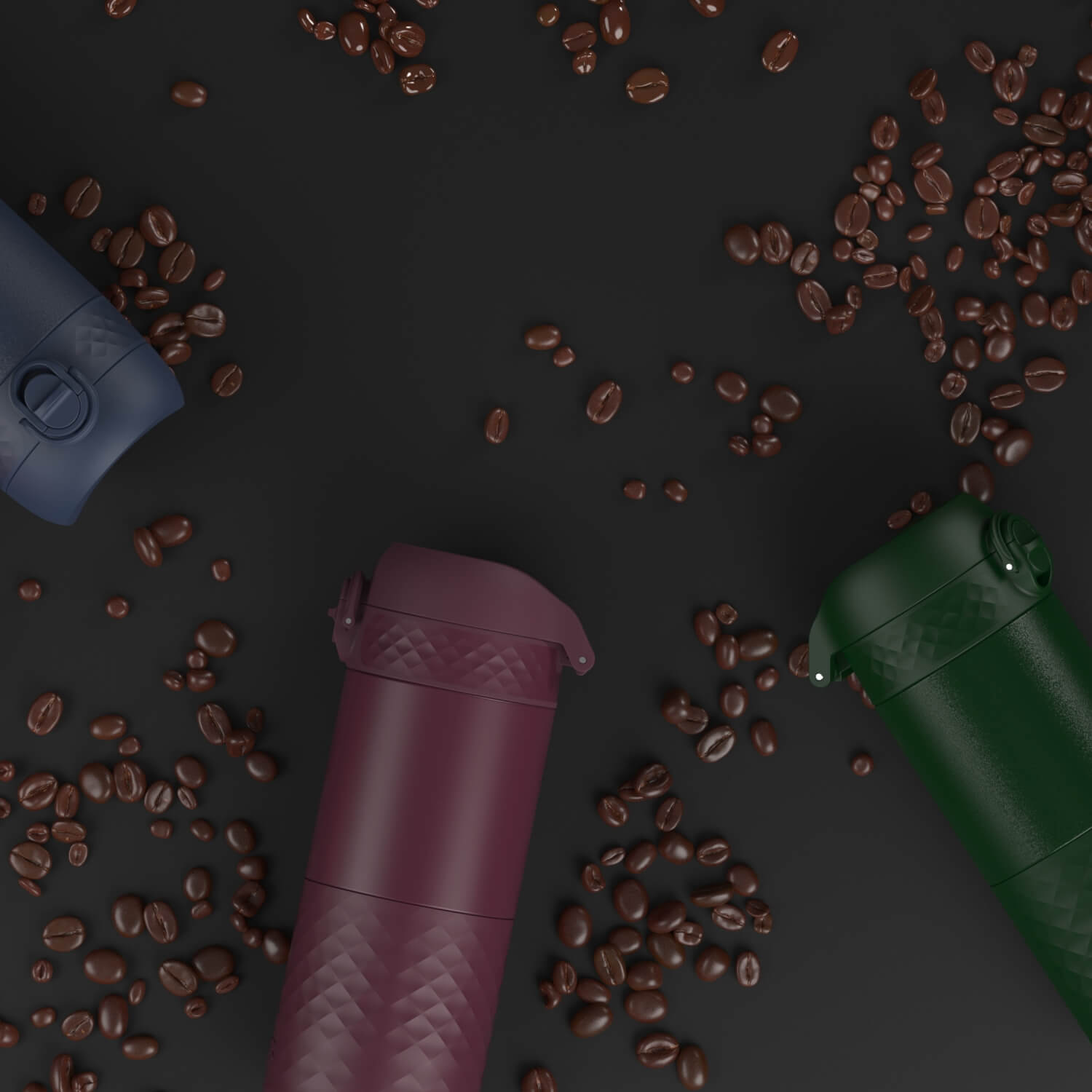 Several portable coffee makers, in various colors, are scattered on a dark surface amongst coffee beans.