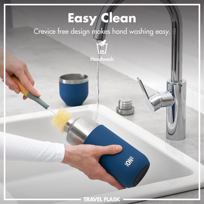 A person cleans a blue travel flask labeled "ION8" with a brush under a running faucet in a kitchen. Text: Easy Clean Crevice free design makes hand washing easy Handwash TRAVEL FLASK