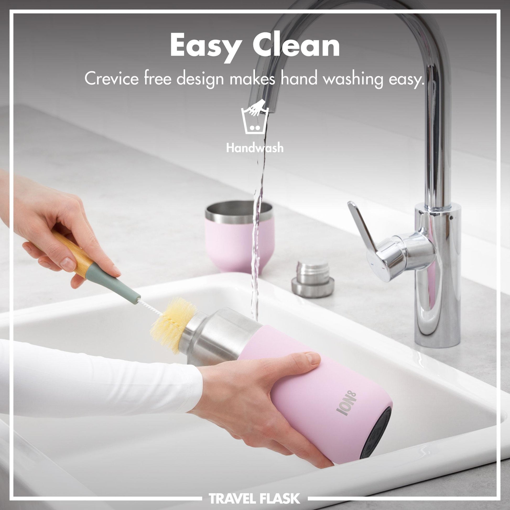 A person cleans a pink travel flask with a brush under running water in a kitchen sink. Text reads Easy Clean Crevice free design makes hand washing easy Handwash Travel Flask.