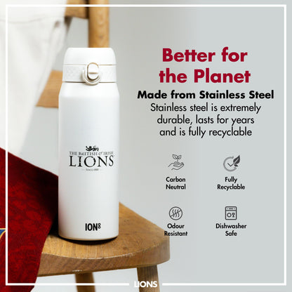 A white, stainless steel water bottle sits on a wooden surface. It features the British & Irish Lions logo and is described as better for the planet, carbon neutral, fully recyclable, odour resistant, and dishwasher safe.