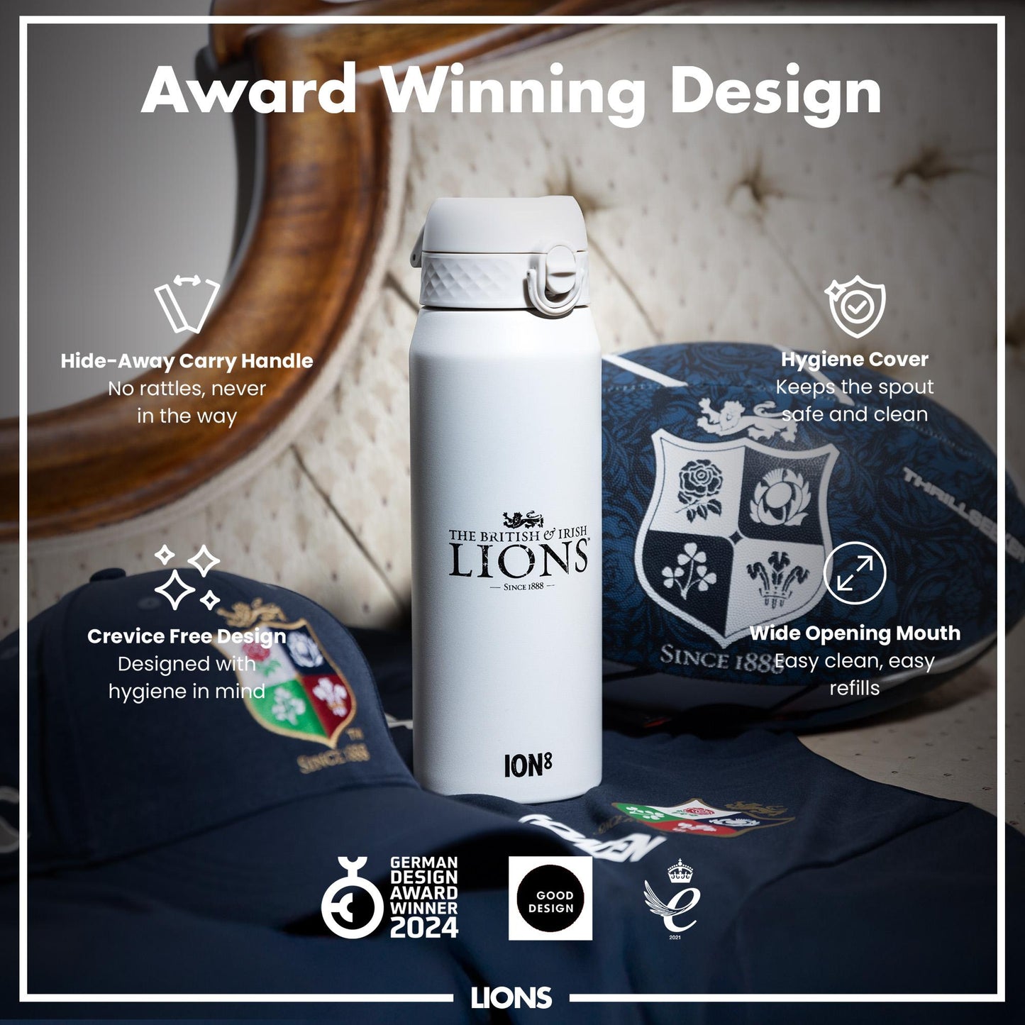 A white water bottle, featuring The British & Irish Lions logo, sits on a dark blue fabric. It has a hide-away handle, hygiene cover, and wide mouth for easy cleaning and refills. The bottle is an award-winning design.