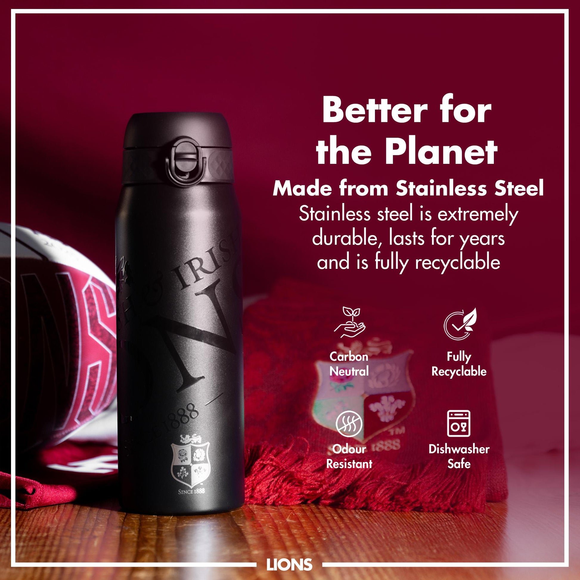 A black stainless steel water bottle sits on a wooden surface. It features an engraved logo. The bottle is presented against a maroon background with text emphasizing its eco-friendly attributes. Better for the Planet. Made from Stainless Steel. Stainless steel is extremely durable, lasts for years and is fully recyclable. Carbon Neutral. Fully Recyclable. Odour Resistant. Dishwasher Safe. LIONS.