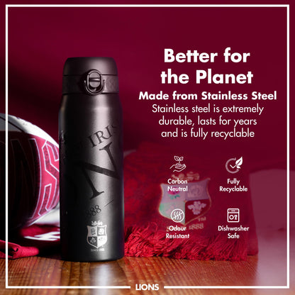 A black stainless steel water bottle sits on a wooden surface. It features an engraved logo. The bottle is presented against a maroon background with text emphasizing its eco-friendly attributes. Better for the Planet. Made from Stainless Steel. Stainless steel is extremely durable, lasts for years and is fully recyclable. Carbon Neutral. Fully Recyclable. Odour Resistant. Dishwasher Safe. LIONS.